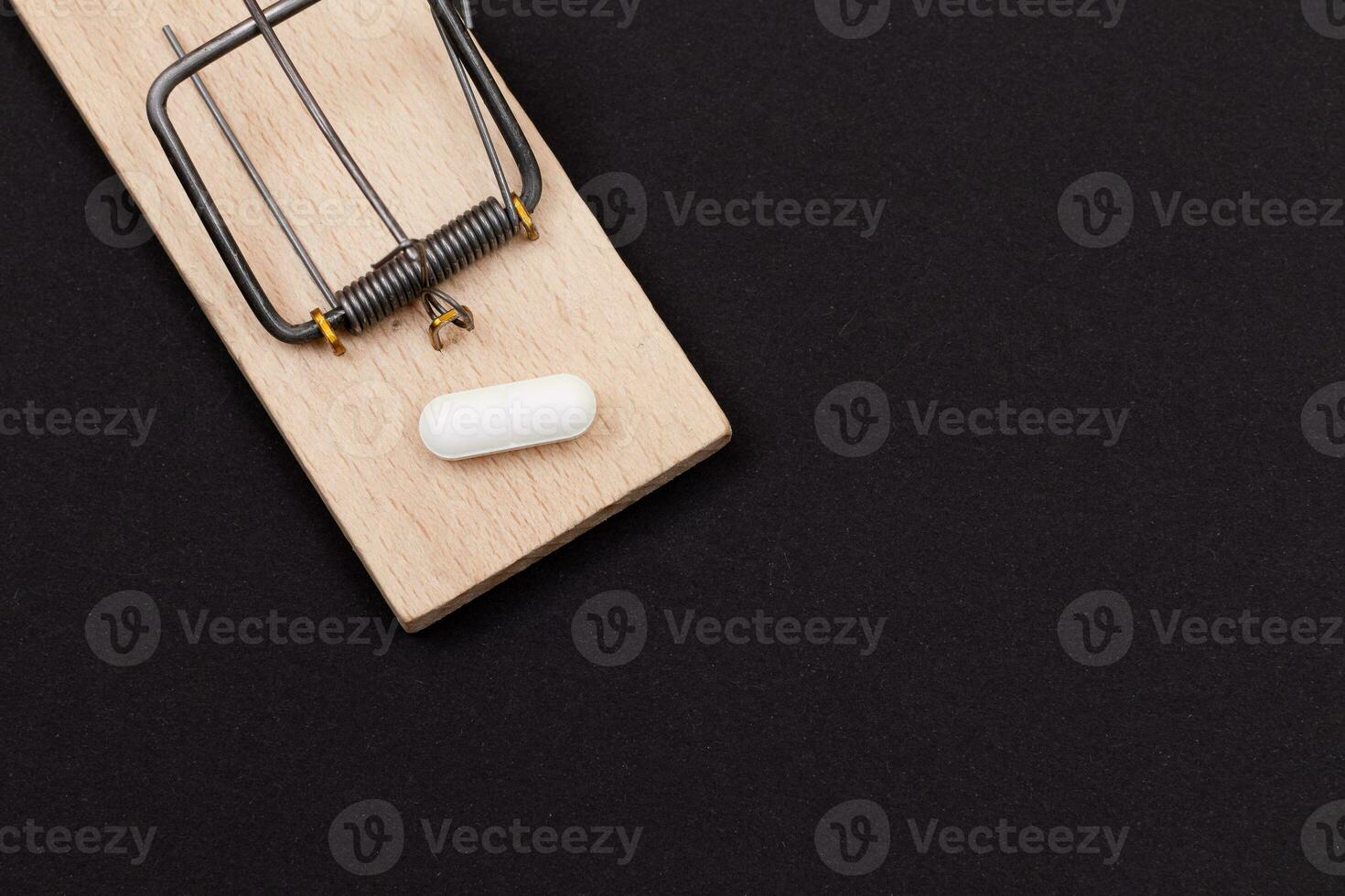 Pharmaceutical Addiction or Big Pharma Trap White Pill in Wooden Mousetrap on Black Background photo