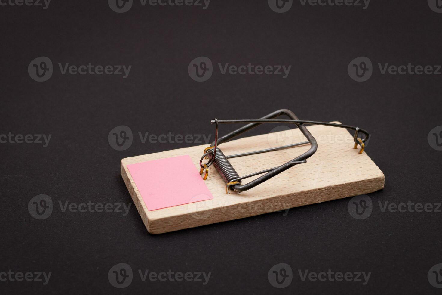 Blank Pink Sheet of Paper in Wooden Mousetrap Template. Small Memo Paper in Mouse Trap on Black Background photo
