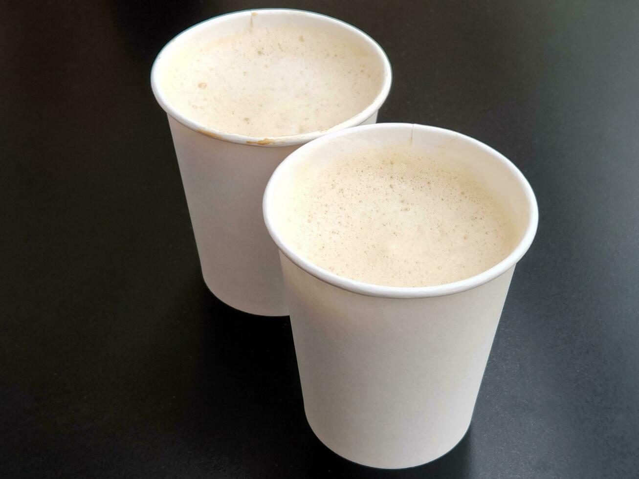 Two cups of coffee. Two paper glasses with coffee on a black background photo