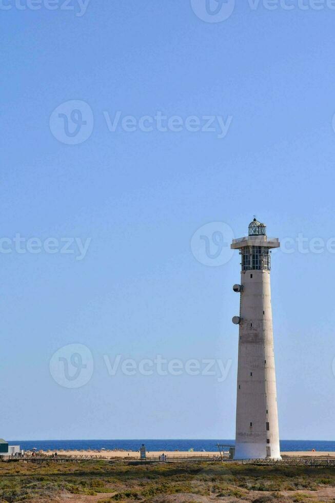 a lighthouse on the beach with a blue sky photo