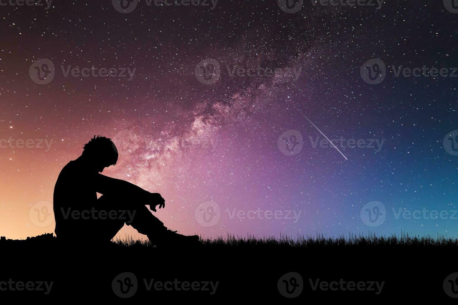 Loneliness, despair and regret concept. Lonely man in the meadow against the backdrop of stars and the Milky Way. photo