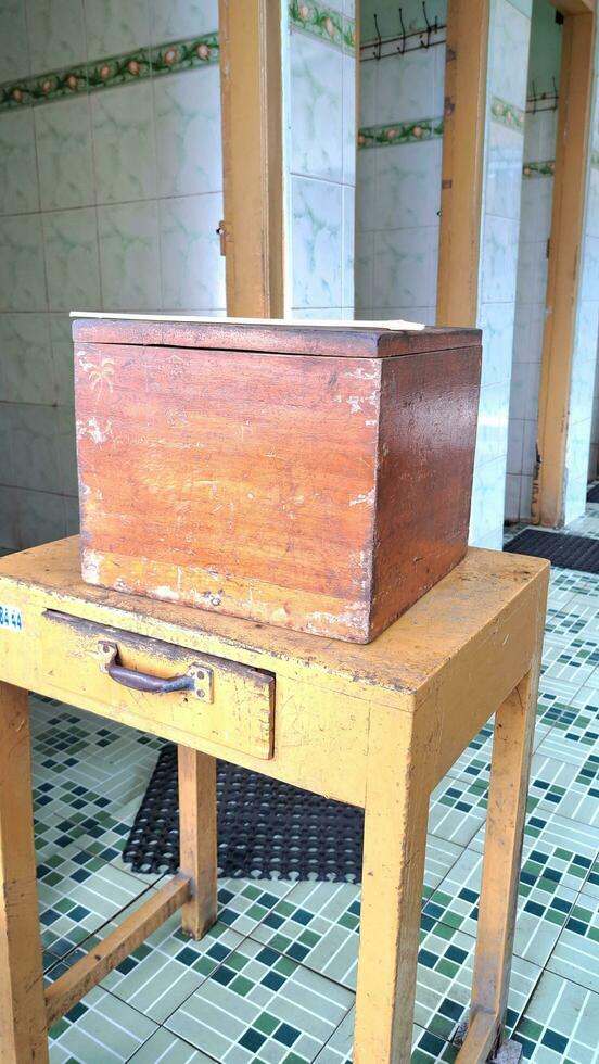 de madera dinero caja en frente de el público baño puerta, adecuado para publicidad único y antiguo elementos, tomando retrato fotos