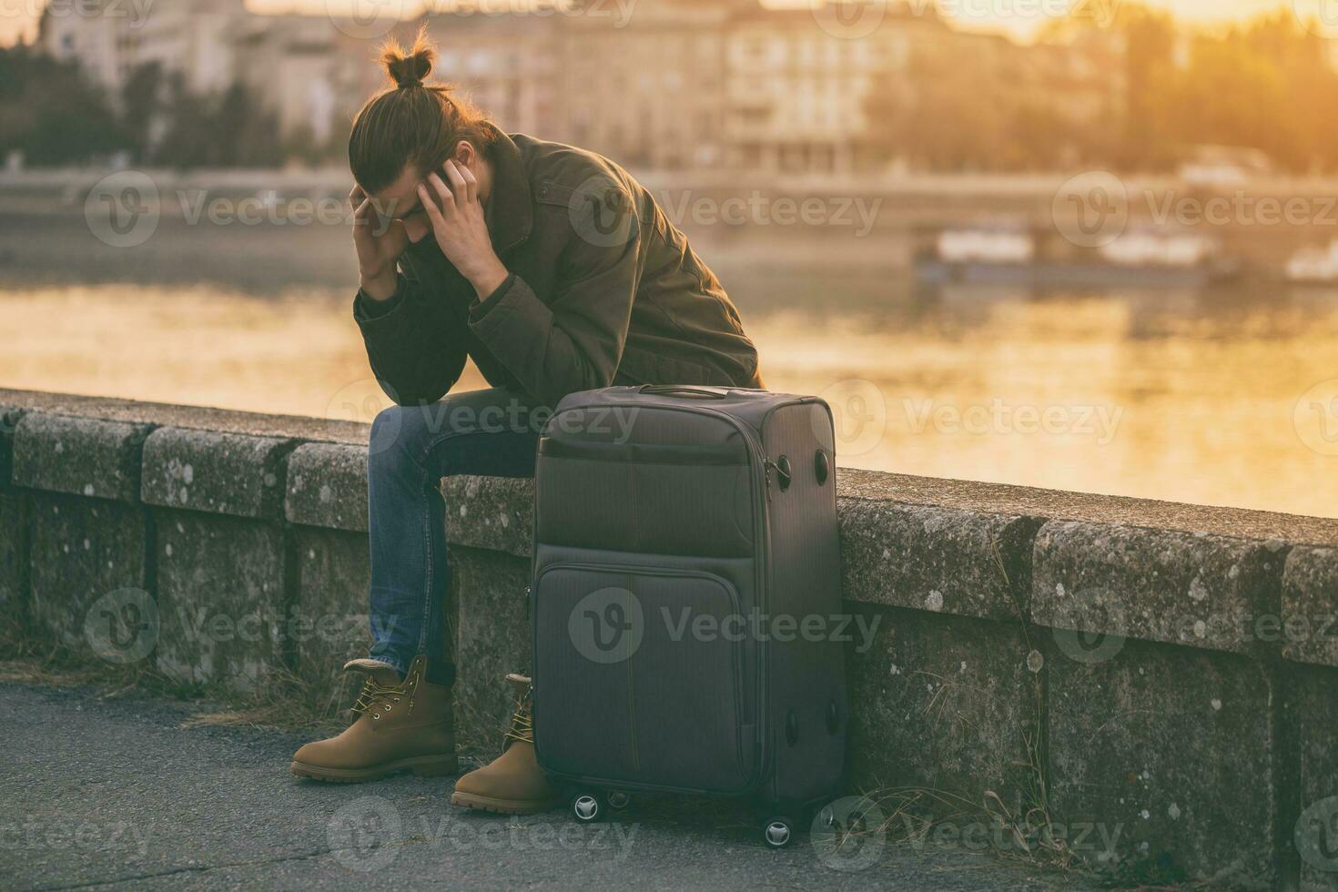 Desperate businessman with suitcase sitting lost by the river.Toned image. photo