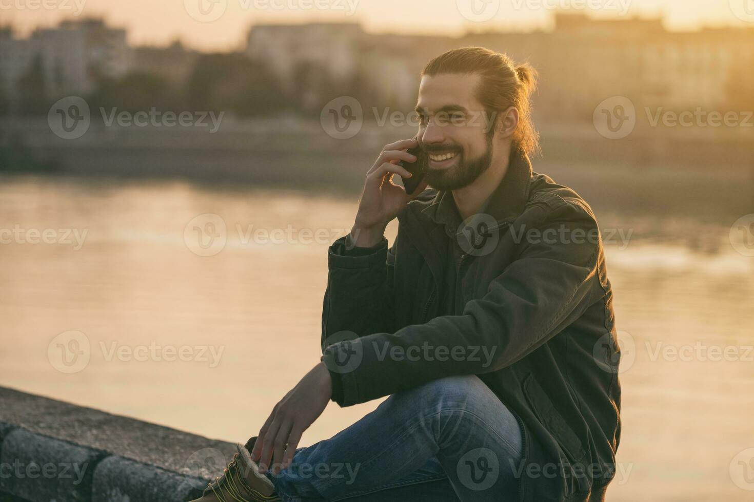 Handsome modern businessman using phone while sitting by the river.Toned image. photo