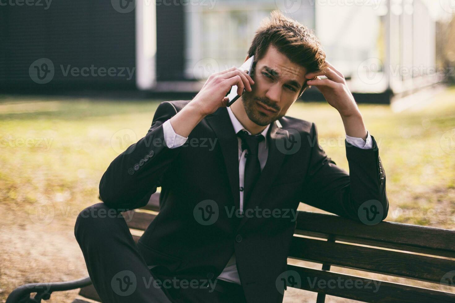 Worried businessman using phone while sitting outdoor.Toned image. photo
