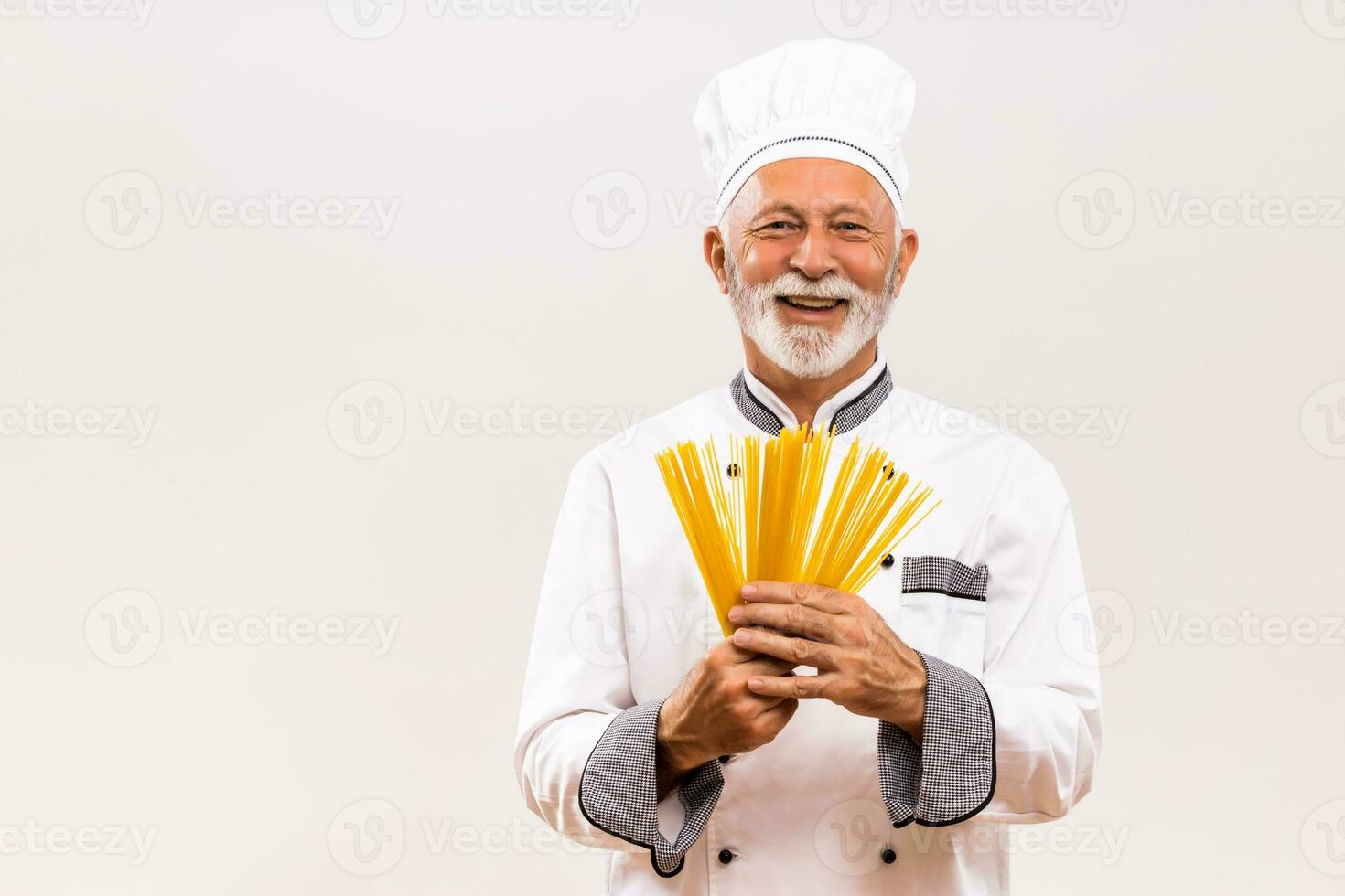 Portrait of senior chef holding spaghetti on gray background. photo