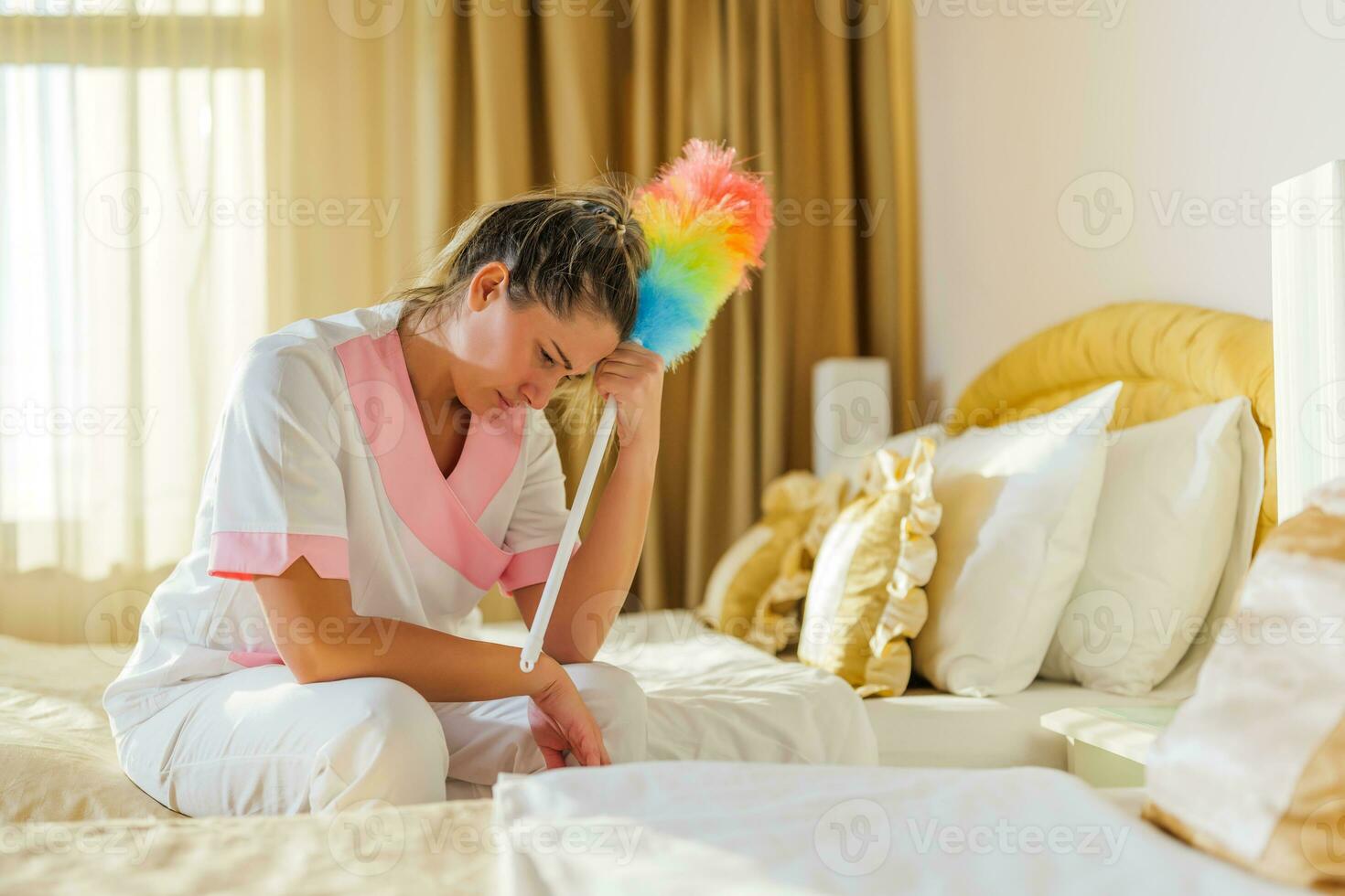 Image of sad overworked hotel maid sitting on the bed in a room. photo