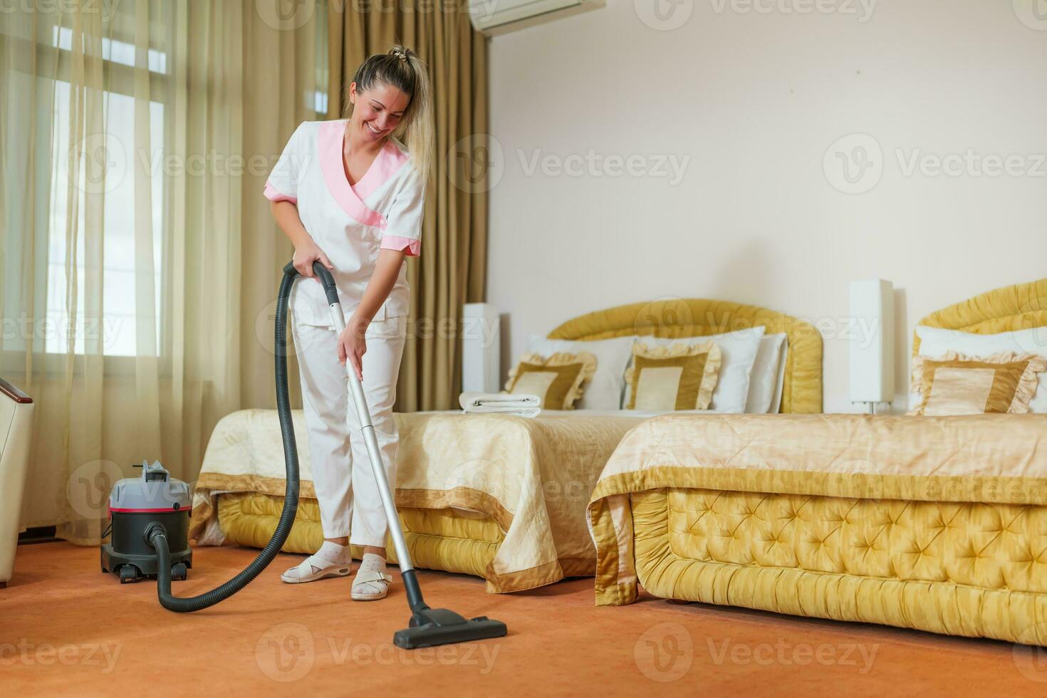 Beautiful hotel maid vacuuming room. photo