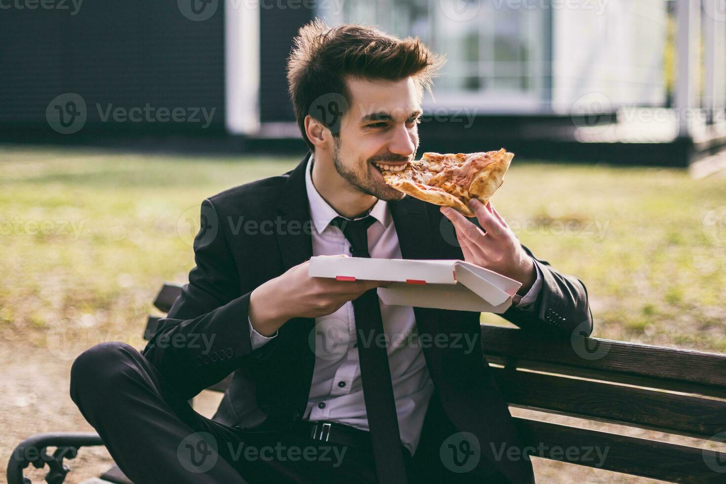 elegante empresario disfruta comiendo Pizza en su almuerzo descanso mientras sentado al aire libre imagen. foto