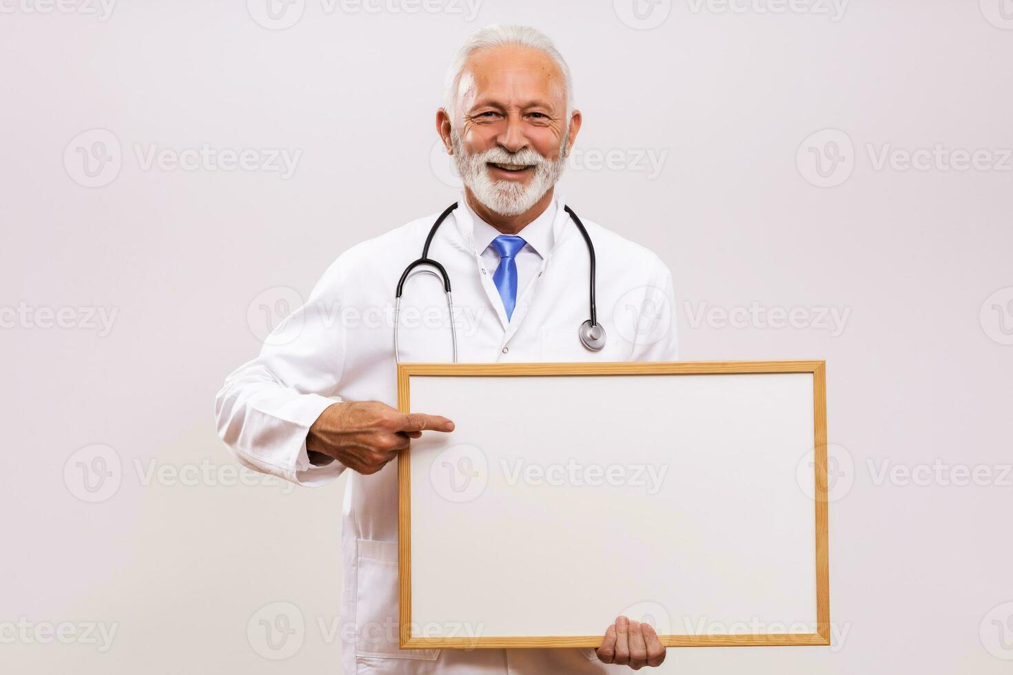 Portrait of senior doctor holding white board on  gray background. photo