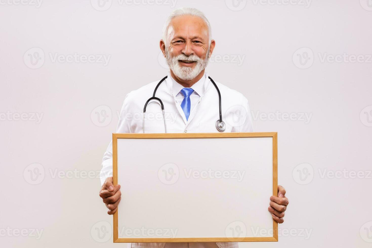 Portrait of senior doctor holding whiteboard on  gray background. photo