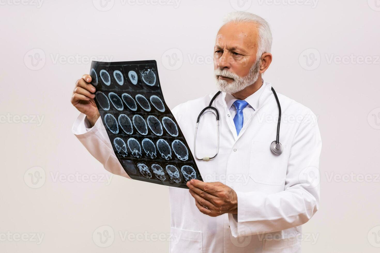 Portrait of worried senior doctor holding x ray image on gray background. photo