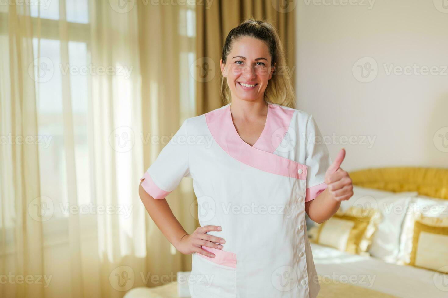 Portrait of beautiful hotel maid showing thumb up. photo