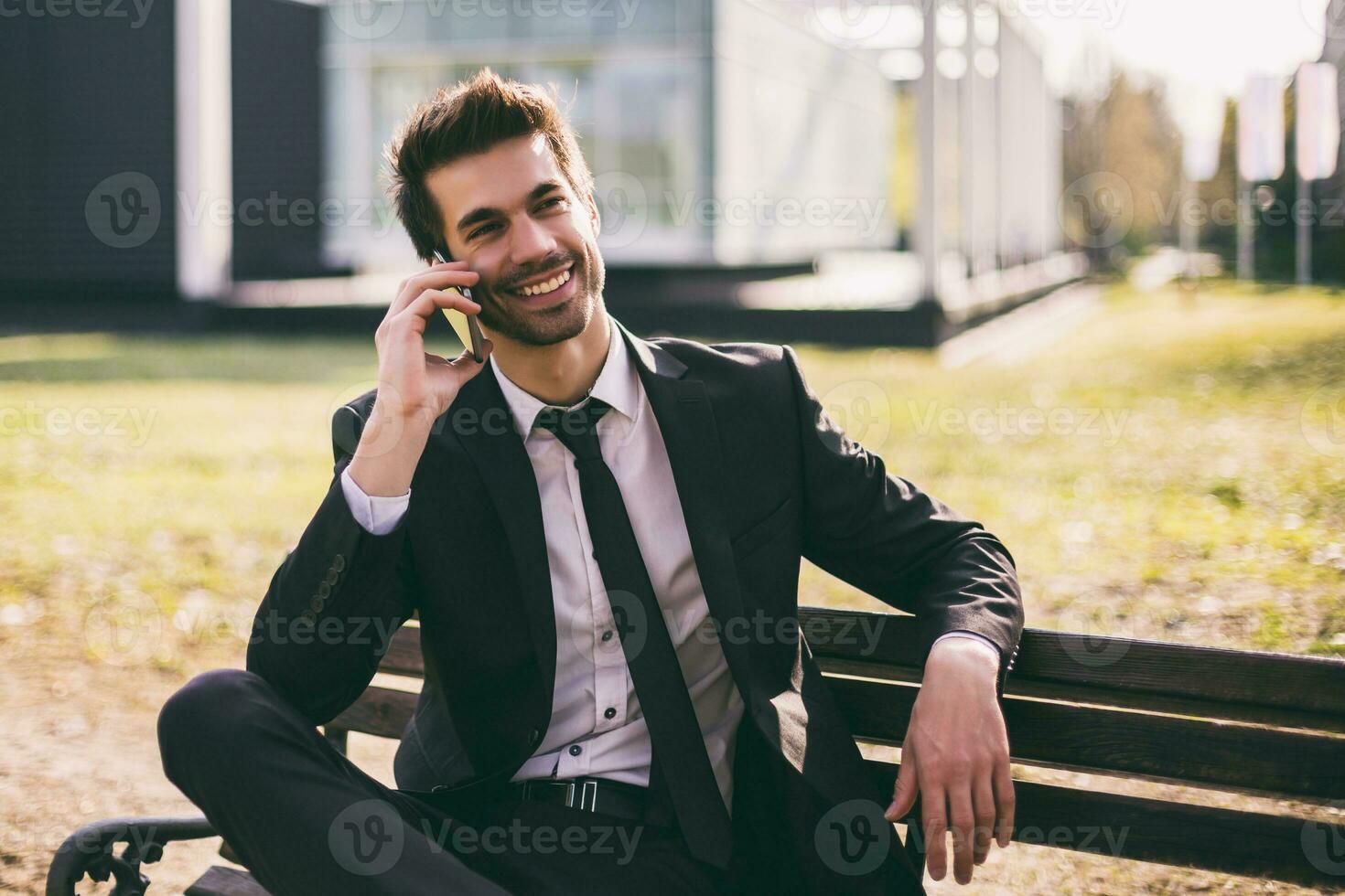 Elegant businessman using phone while sitting outdoor.Toned image photo