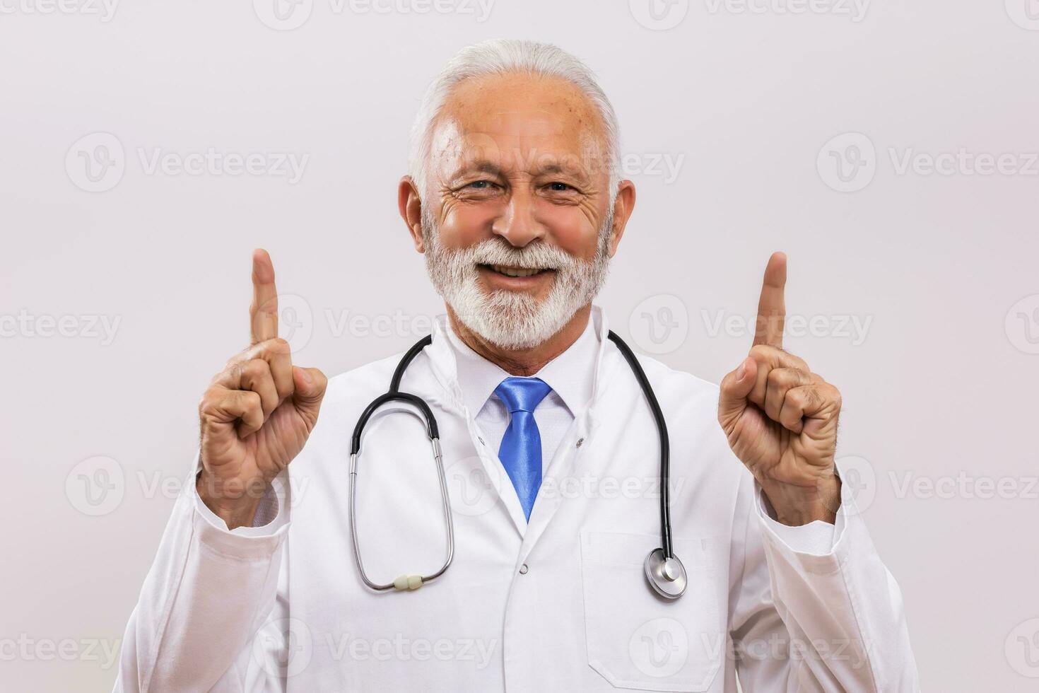 Portrait of senior doctor pointing on gray background. photo