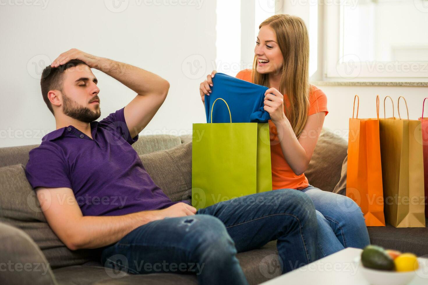Couple having conflict because wife spent too much money on shopping while they sitting at sofa in their home. photo