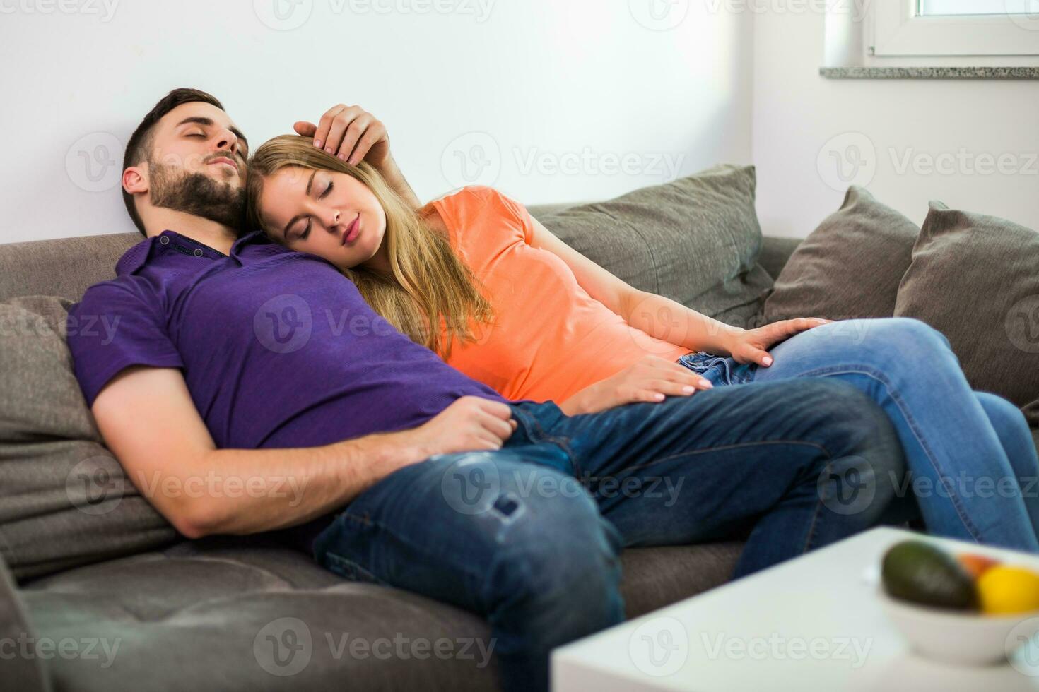Couple enjoys napping together on sofa while they spending time together at their home. photo