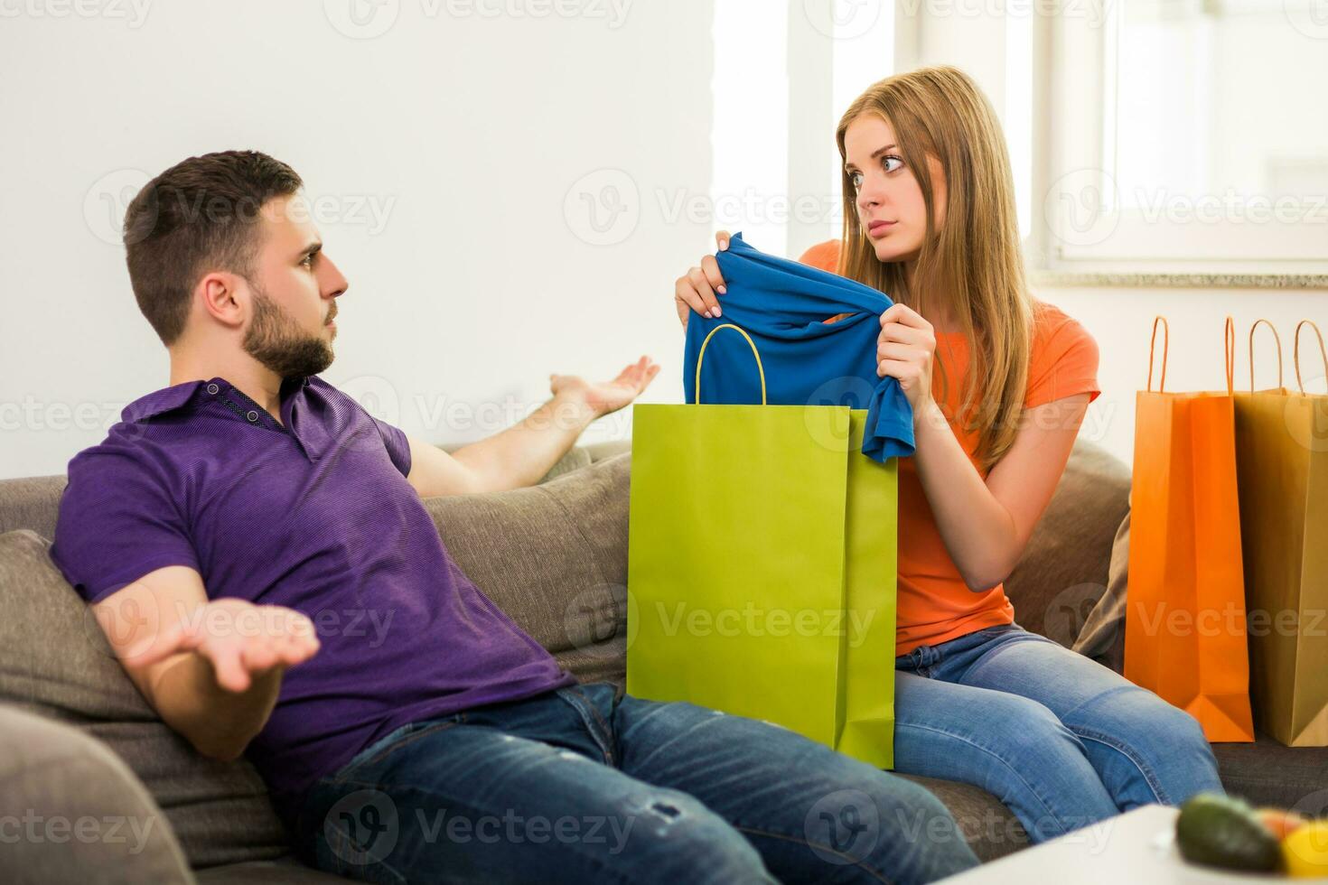 Couple having conflict because wife spent too much money on shopping while they sitting at sofa in their home. photo