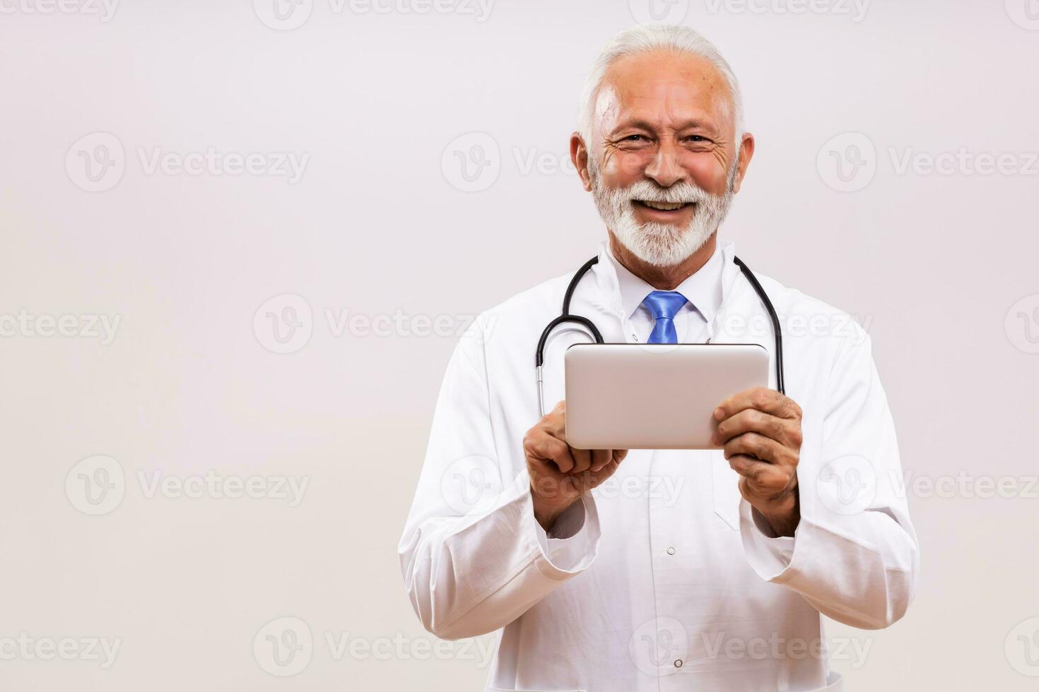 Portrait of senior doctor using digital tablet on gray background. photo