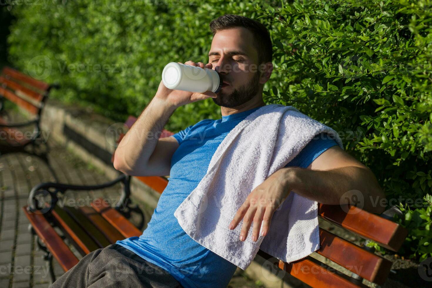 Handsome man drinking water and resting after exercise in the park. photo