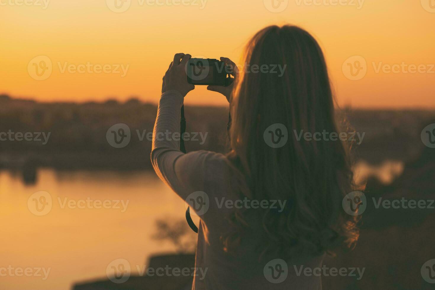 Silhouette of a woman photographing at the sunset. photo