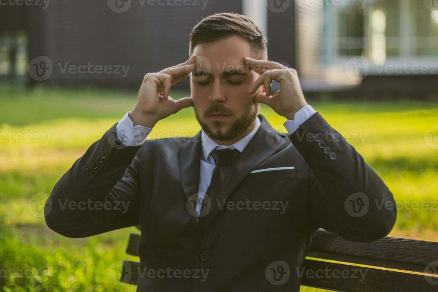 Elegant businessman having a headache while sitting outdoor.Toned image. photo