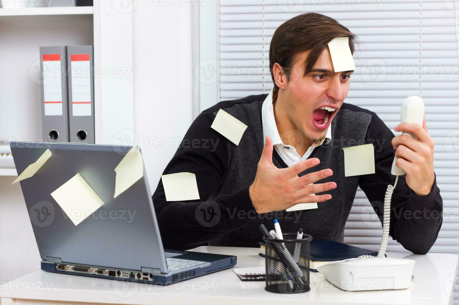 Frustrated businessman shouting at telephone photo