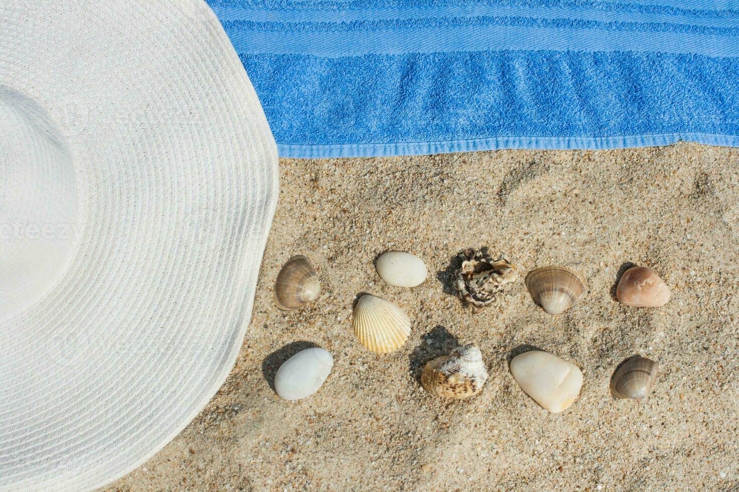 Hat, shells, and a towel on the beach photo