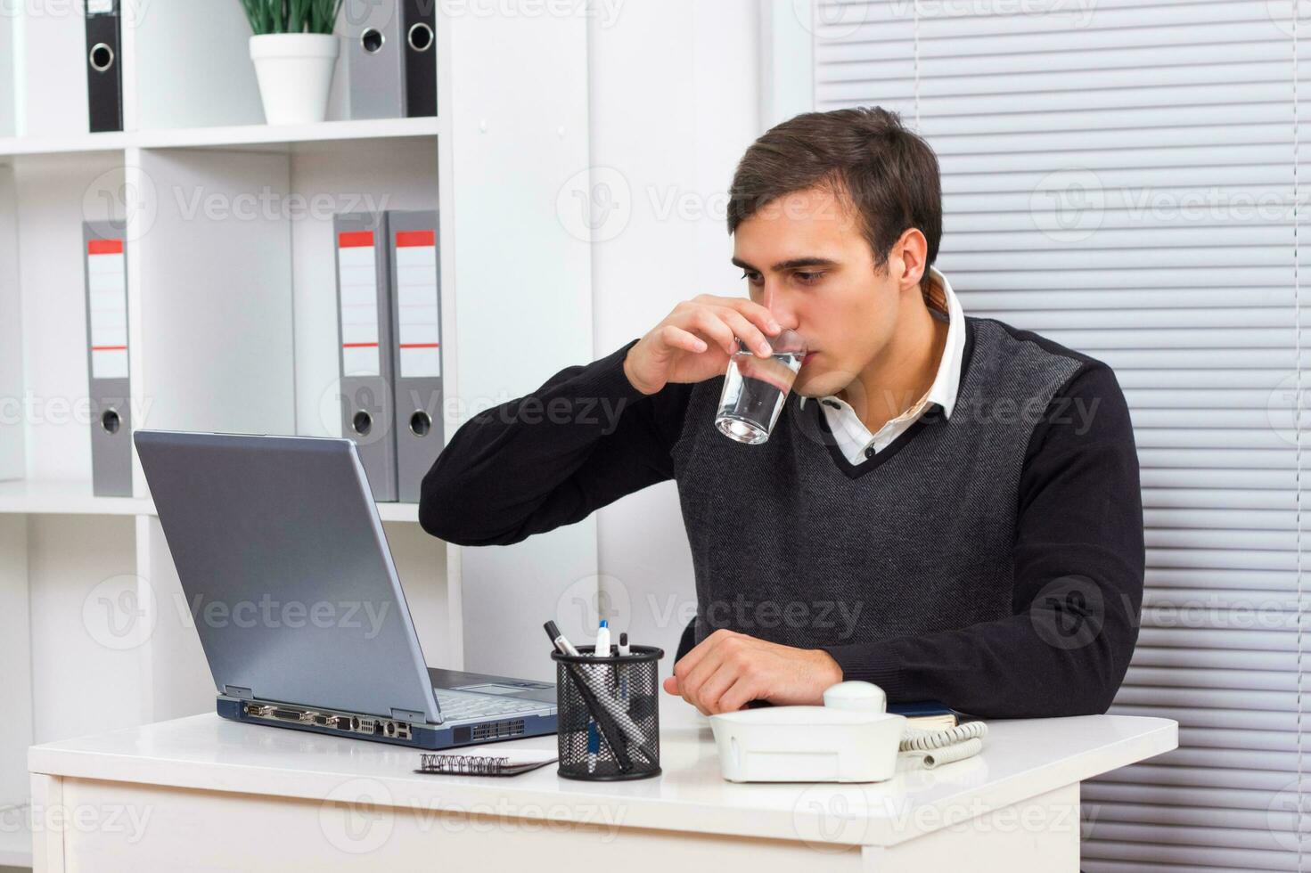 Businessman drinking water while working photo