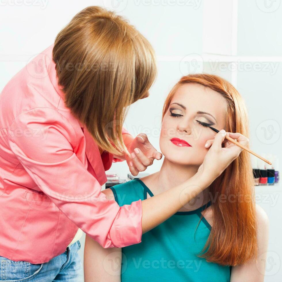 Make up artist applying  make up on a beautiful woman photo