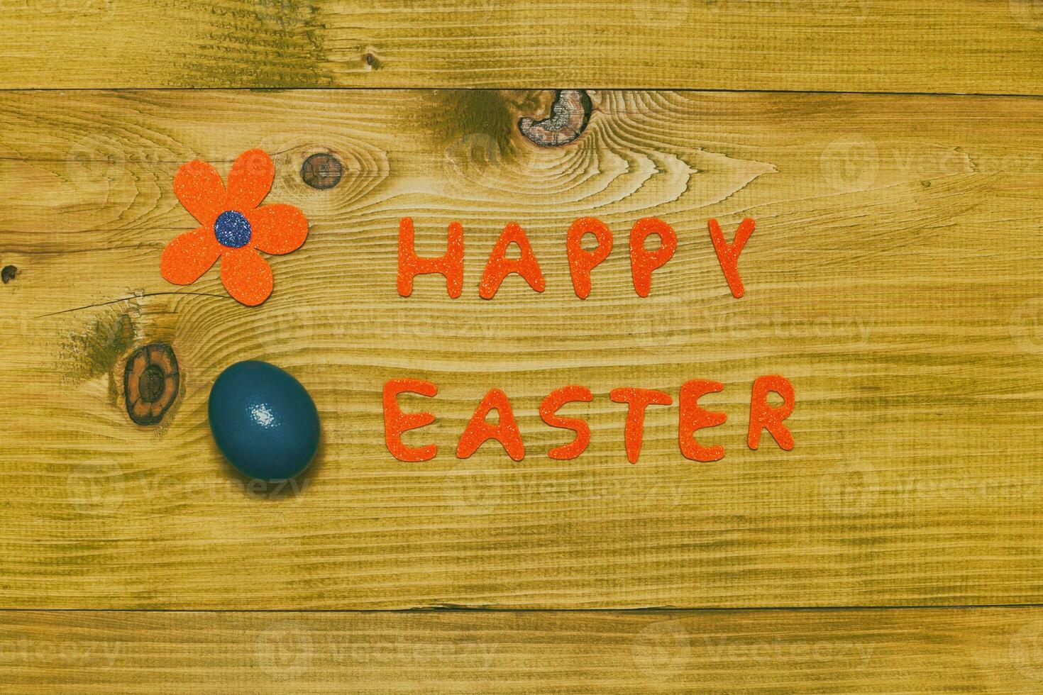 Happy Easter message with painted  egg  and flower on wooden table.Toned photo. photo