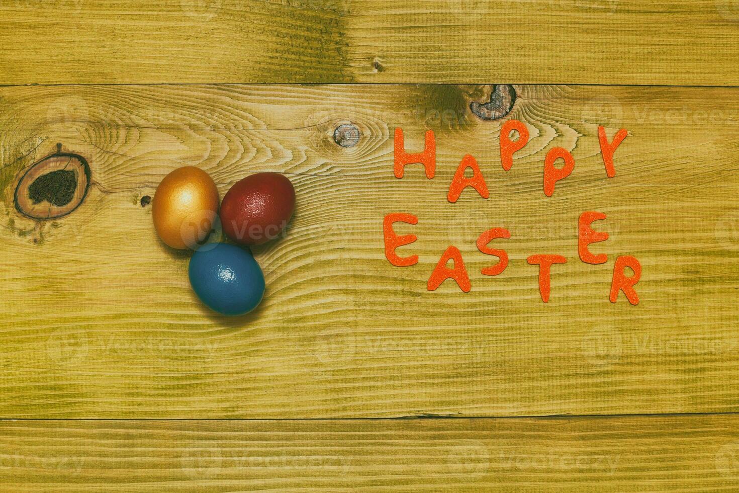 Happy Easter message with painted  eggs  on wooden table.Toned photo. photo