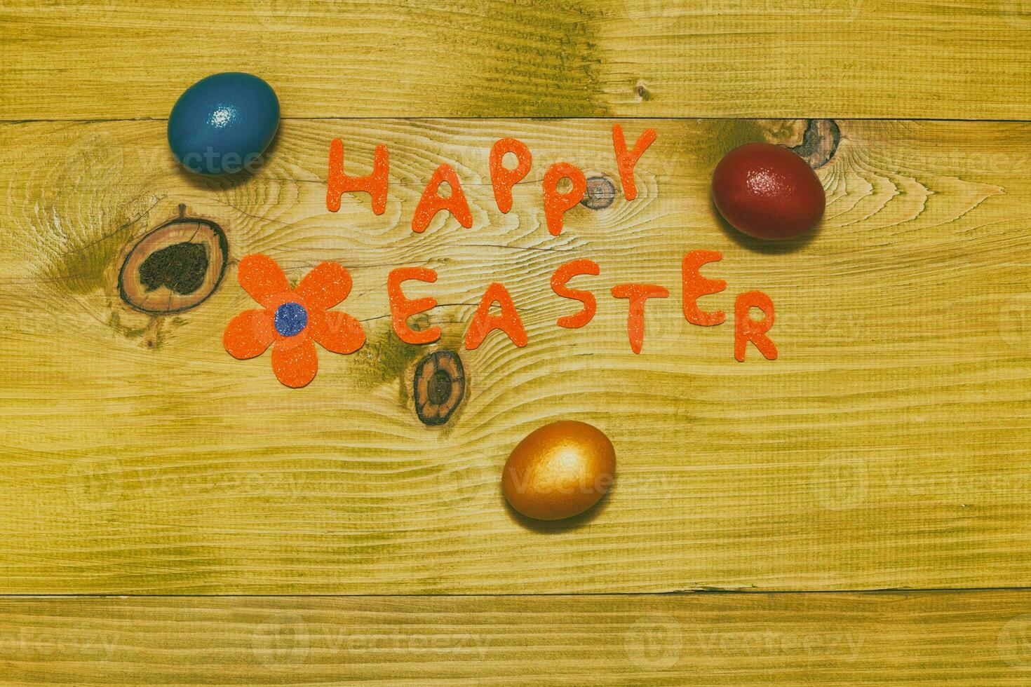 Happy Easter message with painted  eggs  and flower on wooden table.Toned photo. photo