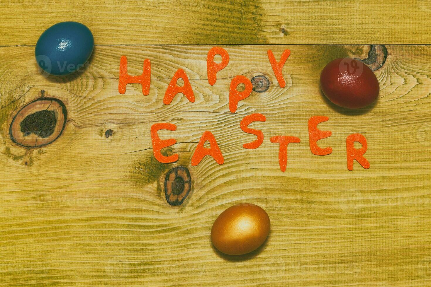 Happy Easter message with painted  eggs  on wooden table.Toned photo. photo