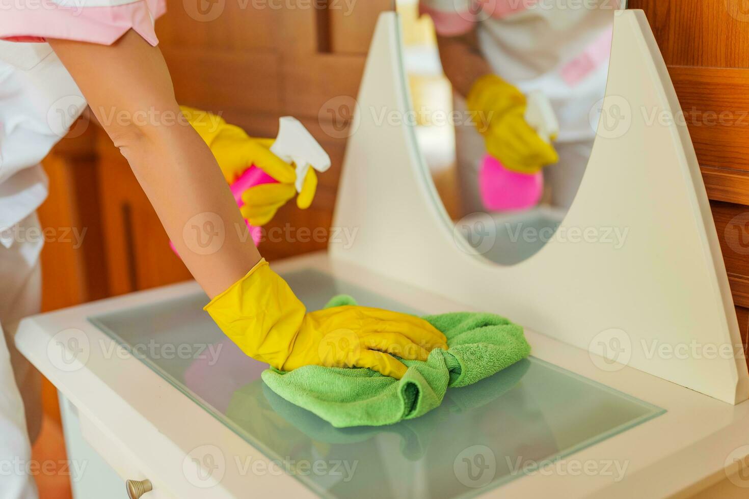 Close up image of hotel maid cleaning furniture in a room. photo