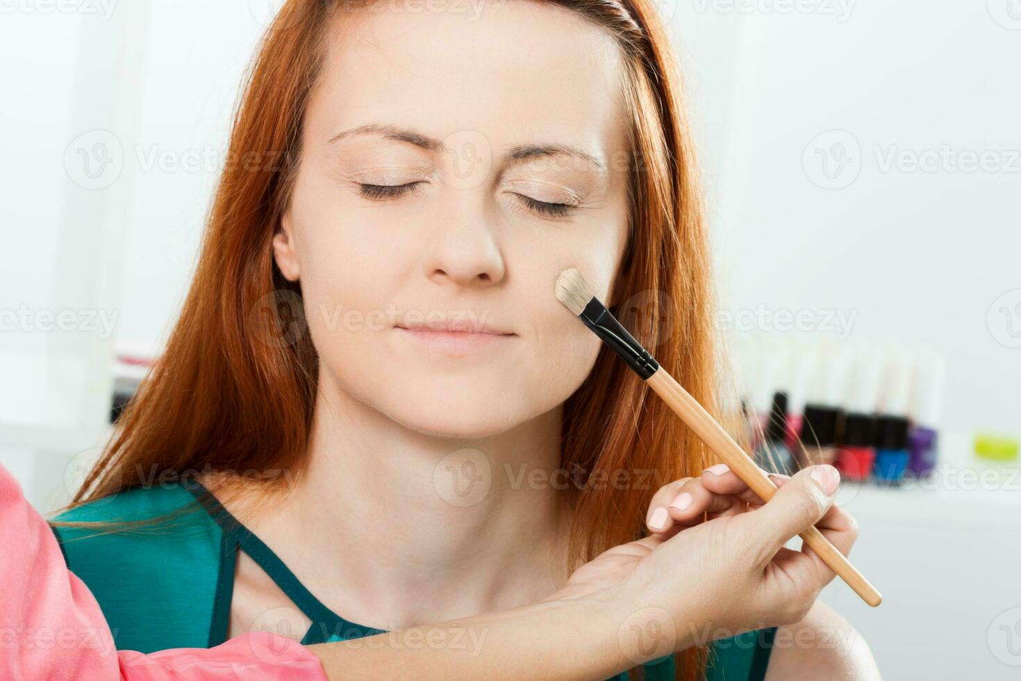 Make up artist applying  make up on a beautiful woman photo