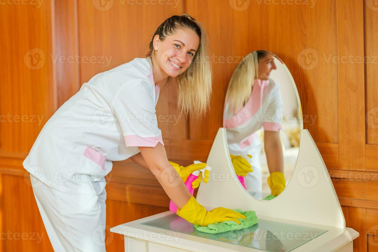 Beautiful hotel maid cleaning furniture in a room. photo