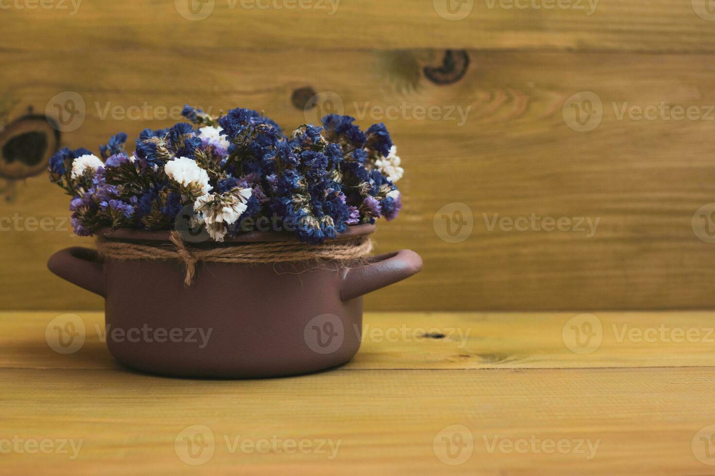 Beautiful dried flowers in cooking pan on wooden background. photo
