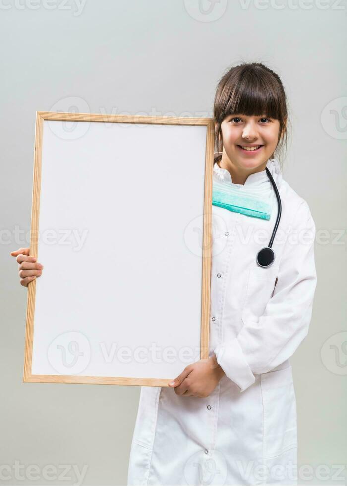 Cheerful little doctor showing whiteboard. photo