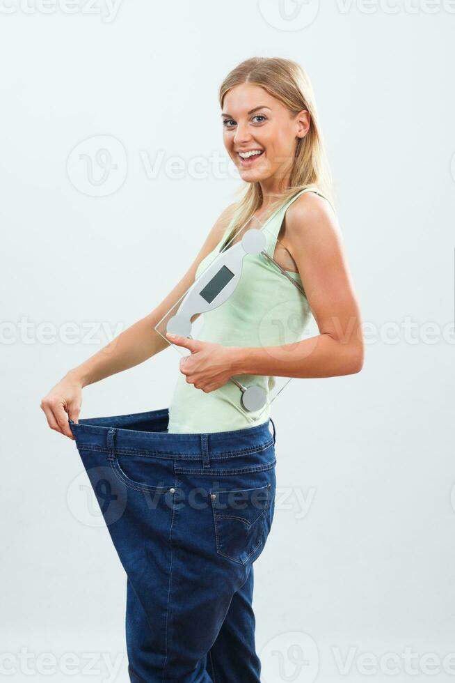 Happy woman in large jeans holding weight scale.Weigt loss concept. photo