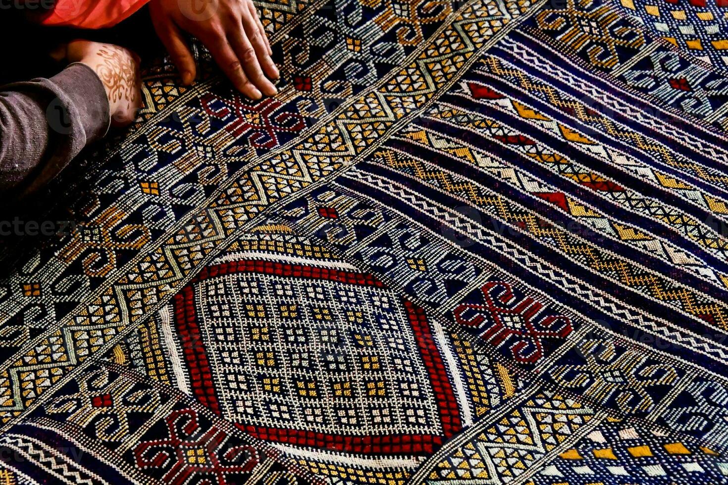 a man sitting on a rug with a colorful pattern photo