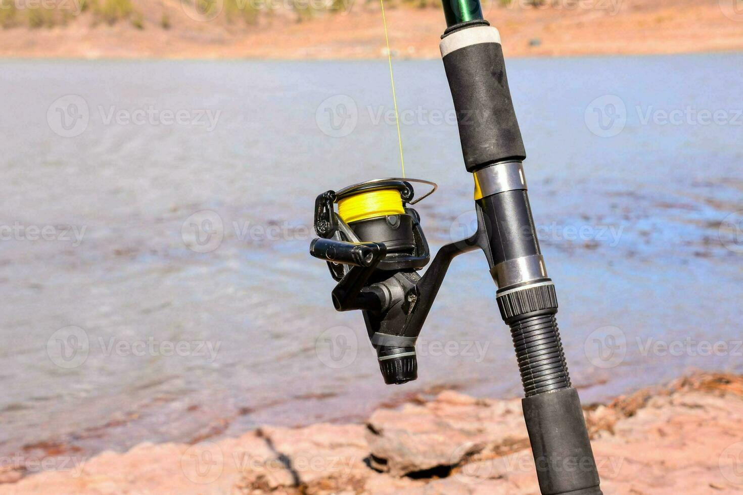 a fishing rod and reel on the shore of a lake photo