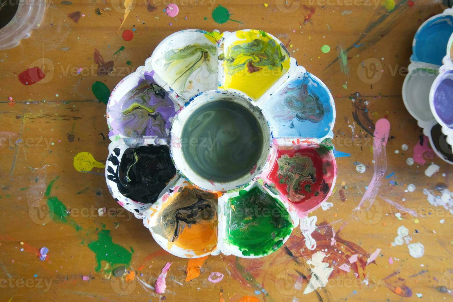 topview photo of a artists watercolour  palette loaded with various colour paints on the wood table no people background.