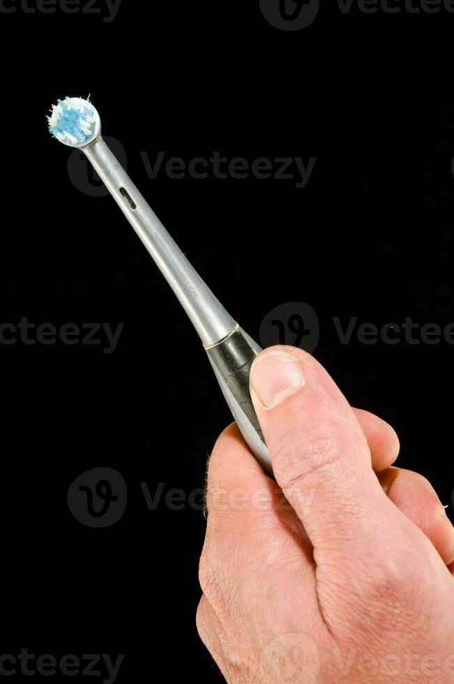 a person holding a toothbrush with a blue tooth photo