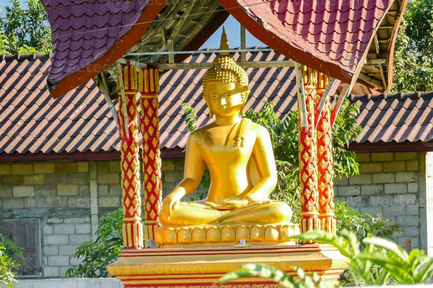 a golden buddha statue sits on top of a red roof photo