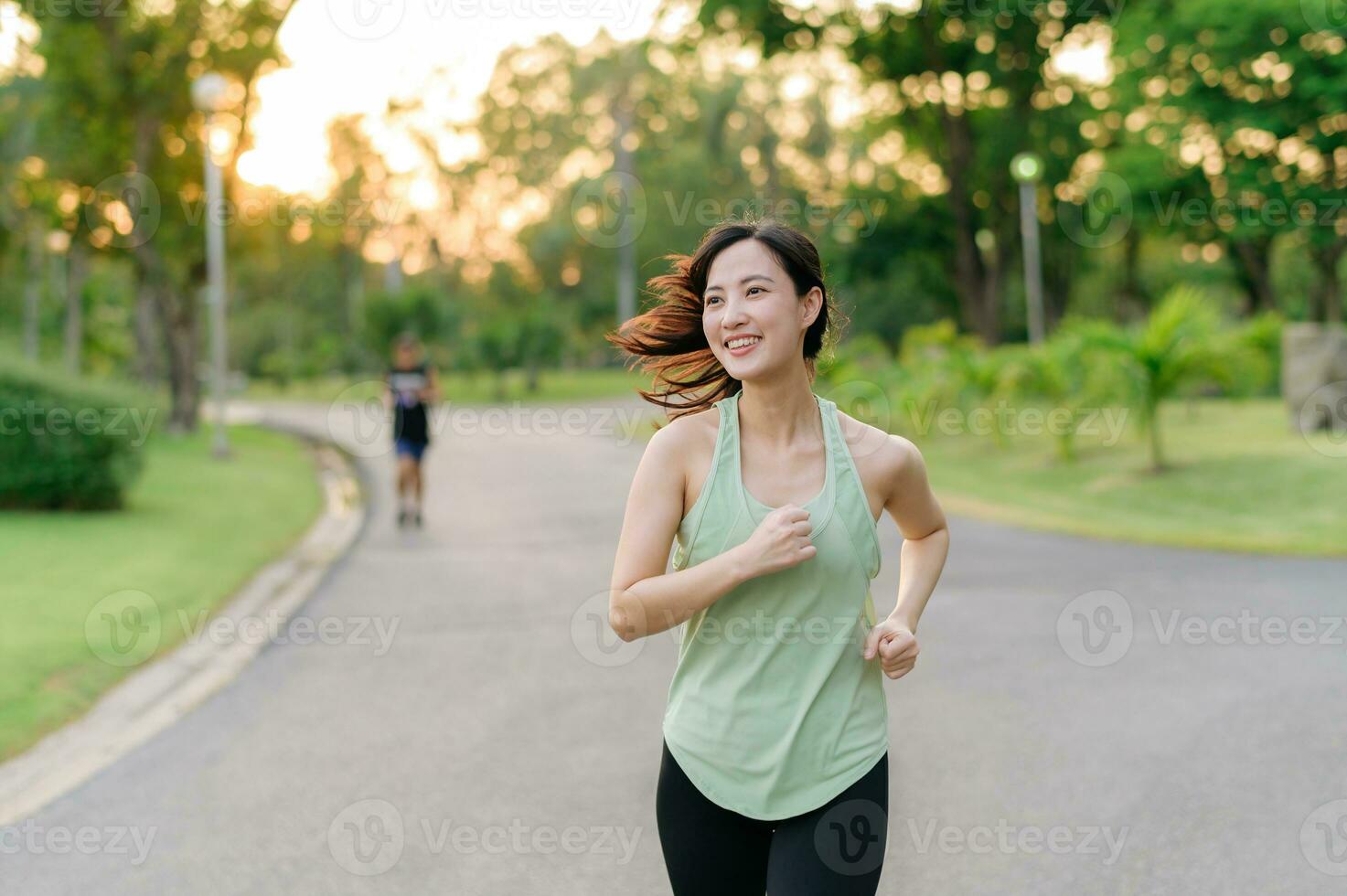 Fit Asian young woman jogging in park smiling happy running and enjoying a healthy outdoor lifestyle. Female jogger. Fitness runner girl in public park. healthy lifestyle and wellness being concept photo