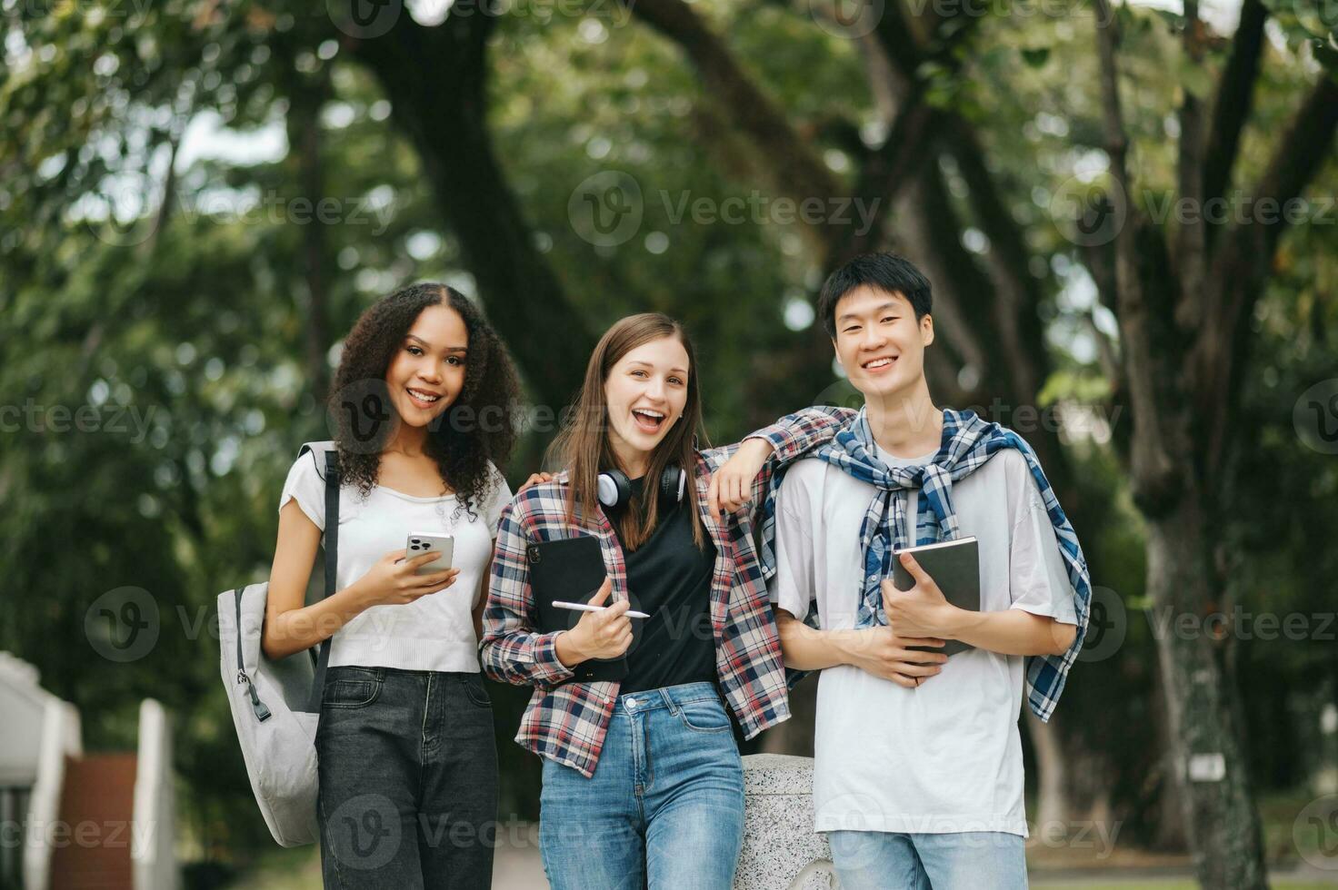 estudiantes son estudiando el instalaciones parque. joven personas son gasto hora juntos. leyendo libro, trabajando con computadora portátil, tableta y comunicado mientras foto