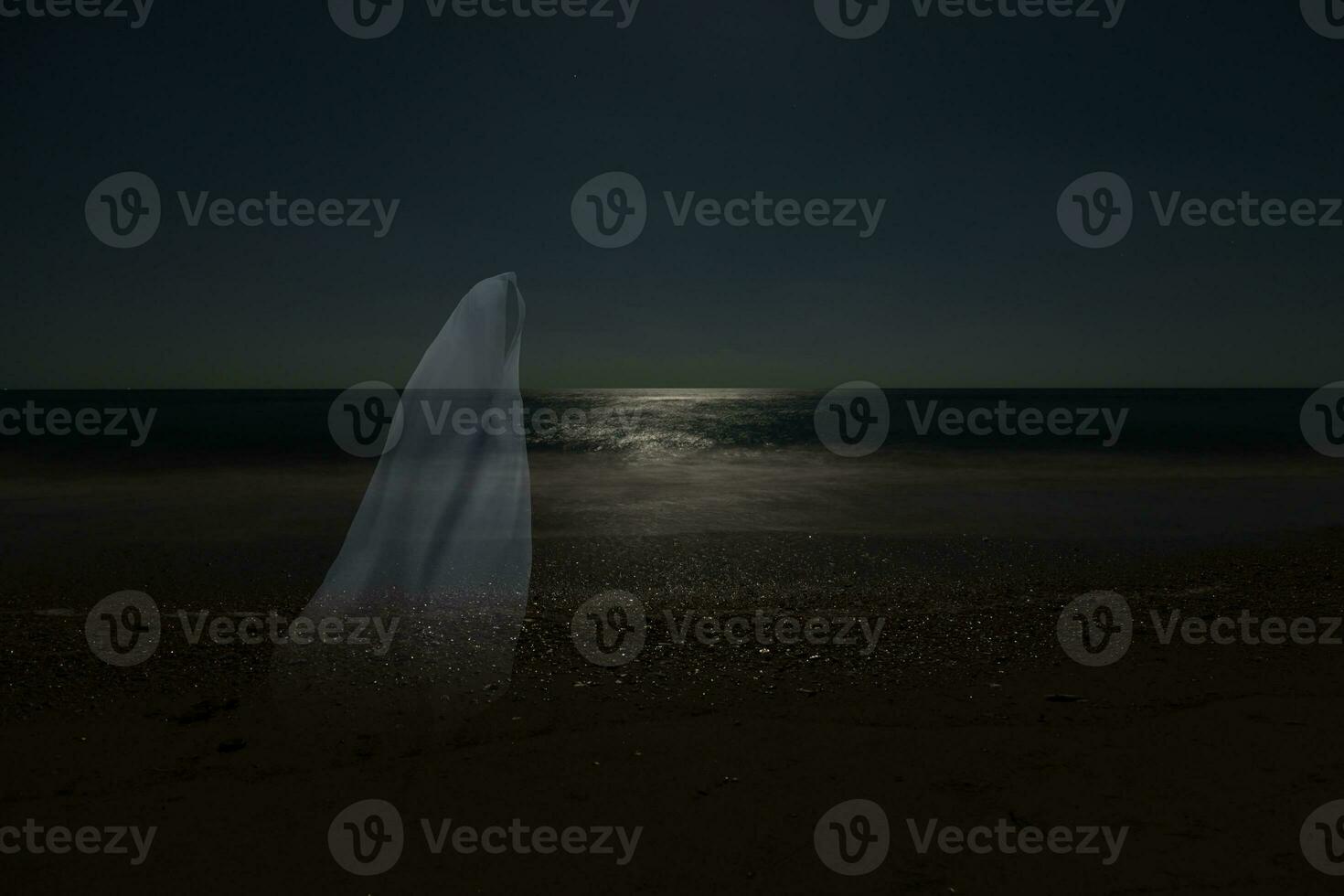 Low key image of ghost in the night on the beach. photo