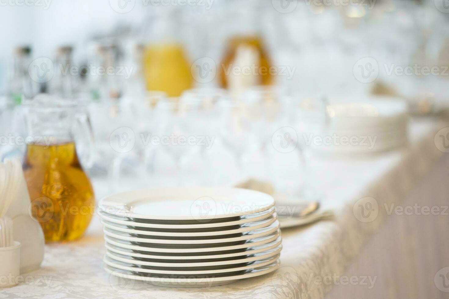 un apilar de blanco platos en el mesa con un jarra de jugo el plastico tazas foto