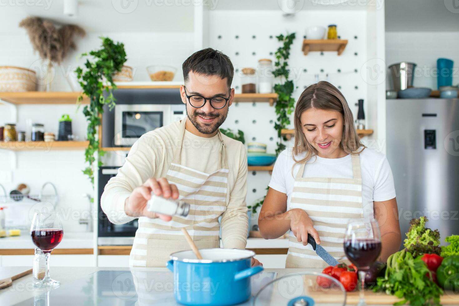 Smiling young couple cooking food in the kitchen together in the kitchen,having a great time together. Man and woman laughing and drinking milk in the morning with breakfast photo